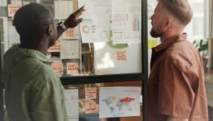 Two Men Are Standing in Front of a Glass Board with Sheets Free Stock Photo by Everypixel